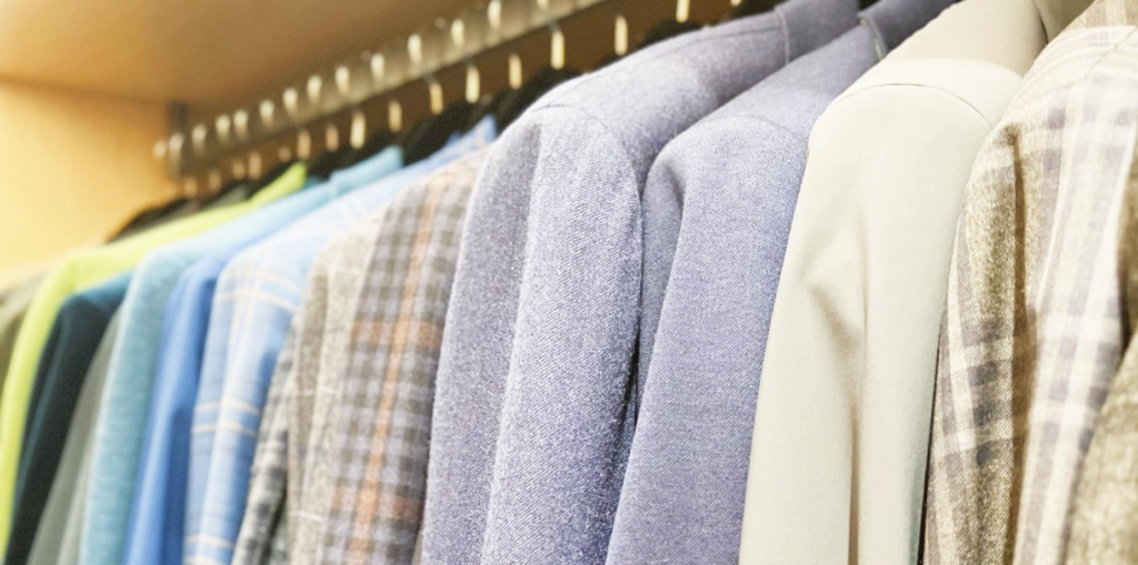 Organizing a clothing rack with coordinated jackets and shirts on hangers, arranged by color for a tidy look.”